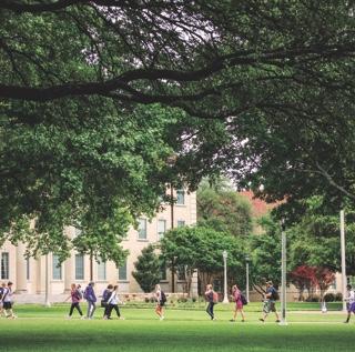 Students seen from a distance walking across campus near TCU's main administration building